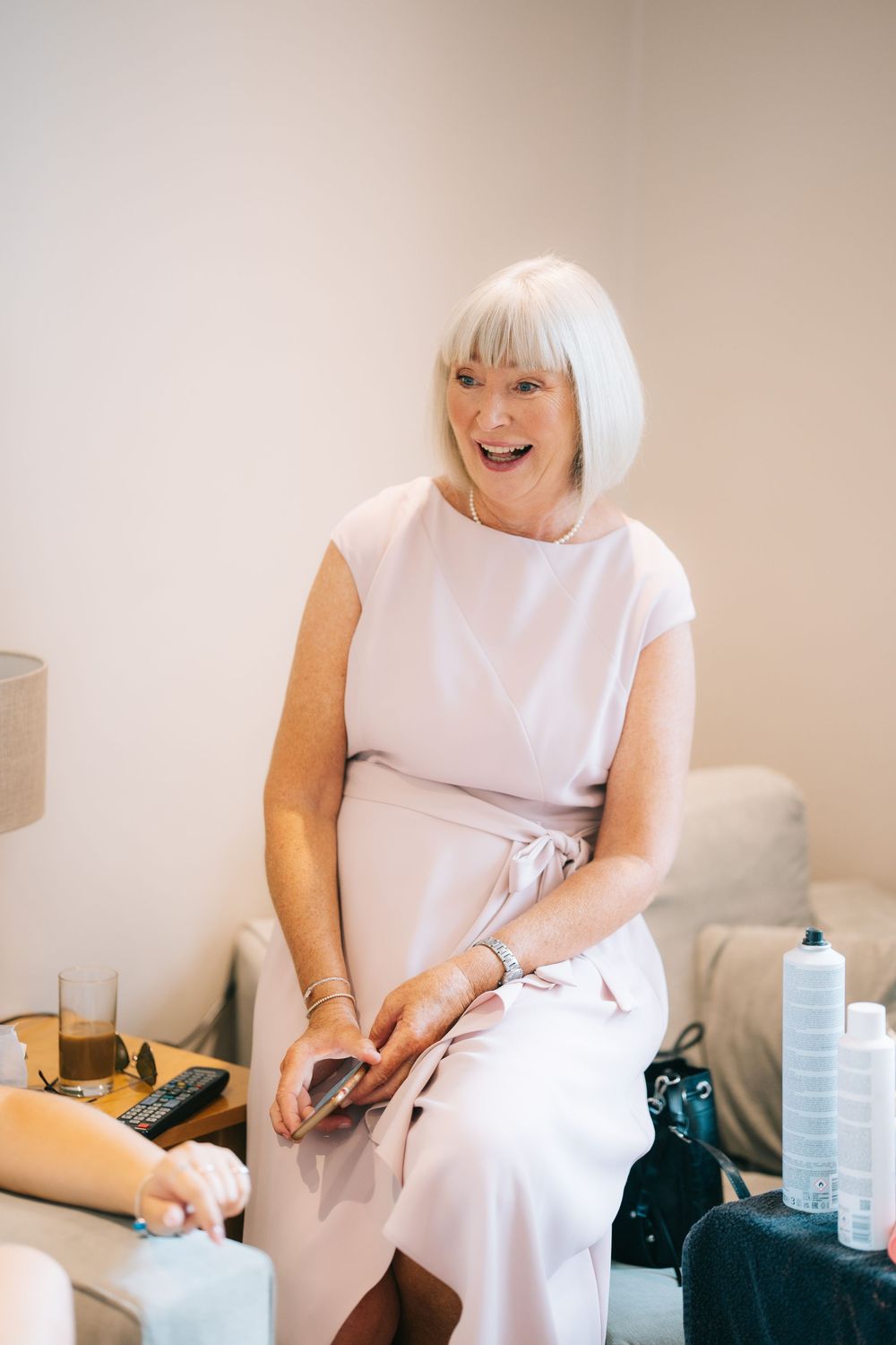 Person in a white dress sits and laughs while getting ready in a bright indoor setting  at Pendrell Hall wedding venue