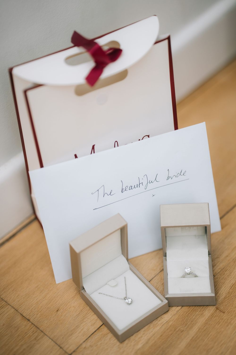 Wedding rings and jewelry boxes arranged in a sequence on a wooden surface with red ribbons  at Pendrell Hall wedding venue