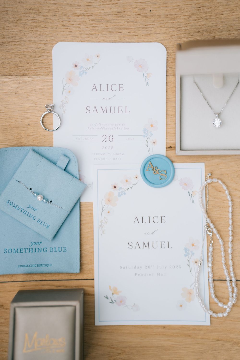 Wedding stationery in light blue and white with names Alice and Samuel displayed on wooden surface  at Pendrell Hall wedding venue
