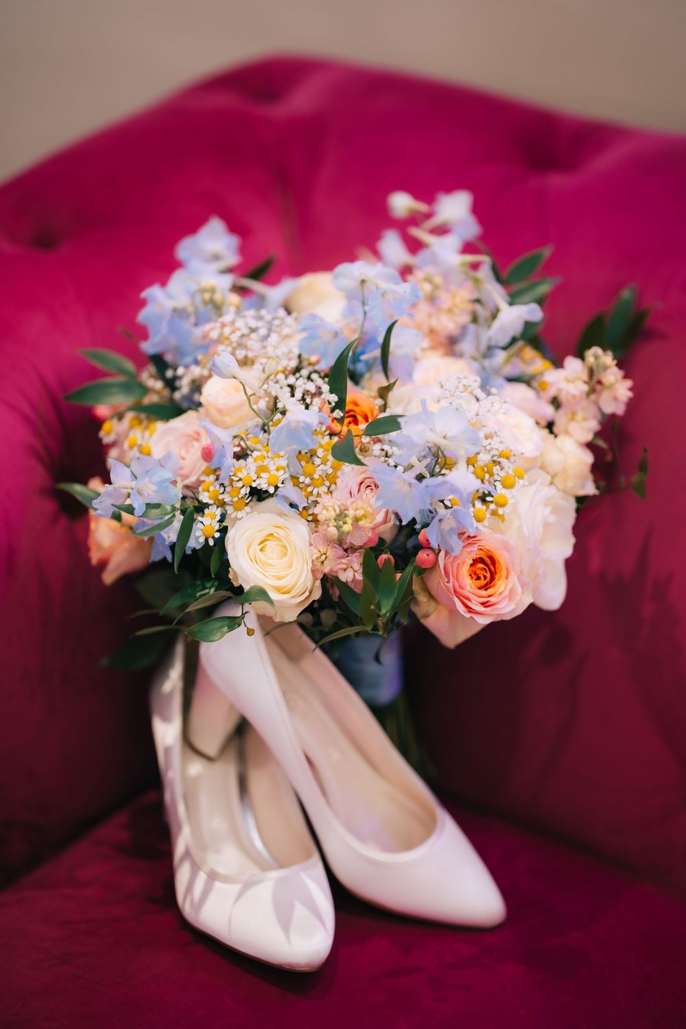 Elegant cream-colored bridal shoes adorned with delicate floral arrangements on burgundy velvet background  at Pendrell Hall wedding venue