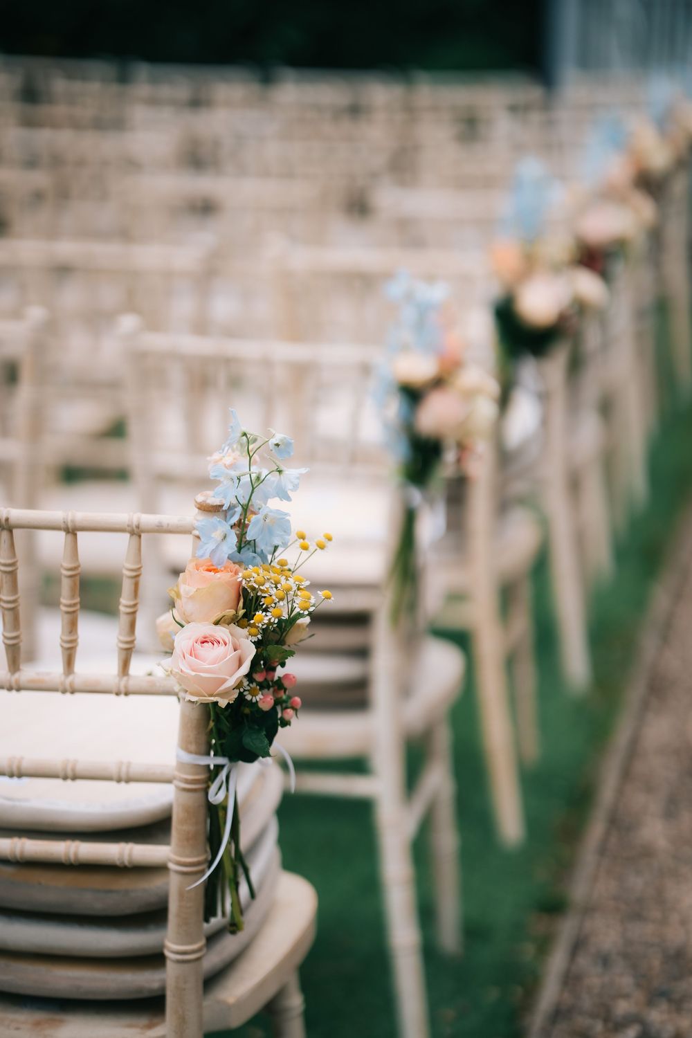 Row of elegant white chairs with delicate floral arrangements for an outdoor wedding ceremony  at Pendrell Hall wedding venue
