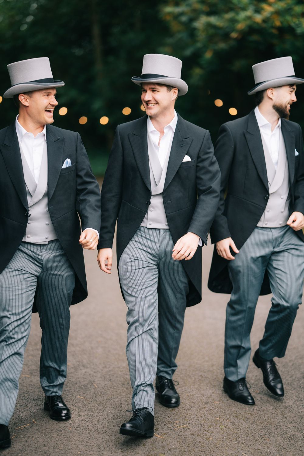 Groomsmen in formal morning suits and top hats walking together in coordinated style at Pendrell Hall wedding venue
