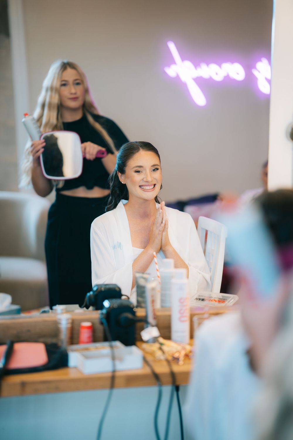 Wedding preparation scene with people getting ready at tables with mirrors and lighting at Pendrell Hall wedding venue