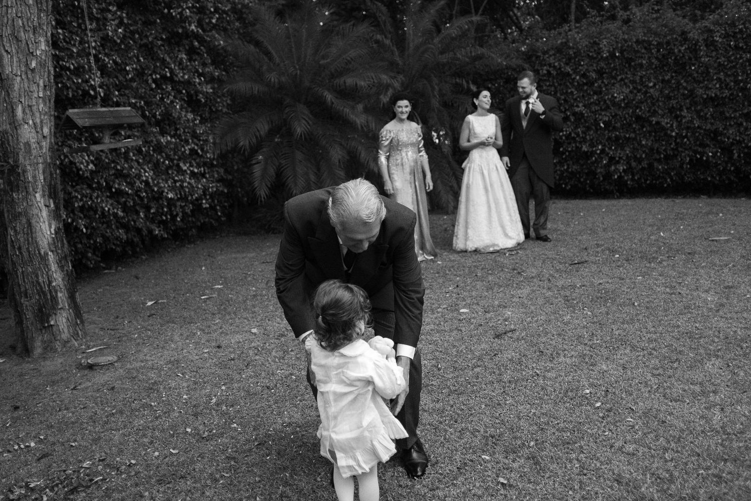 A series of black and white wedding photos showing couples and guests in an outdoor garden setting.