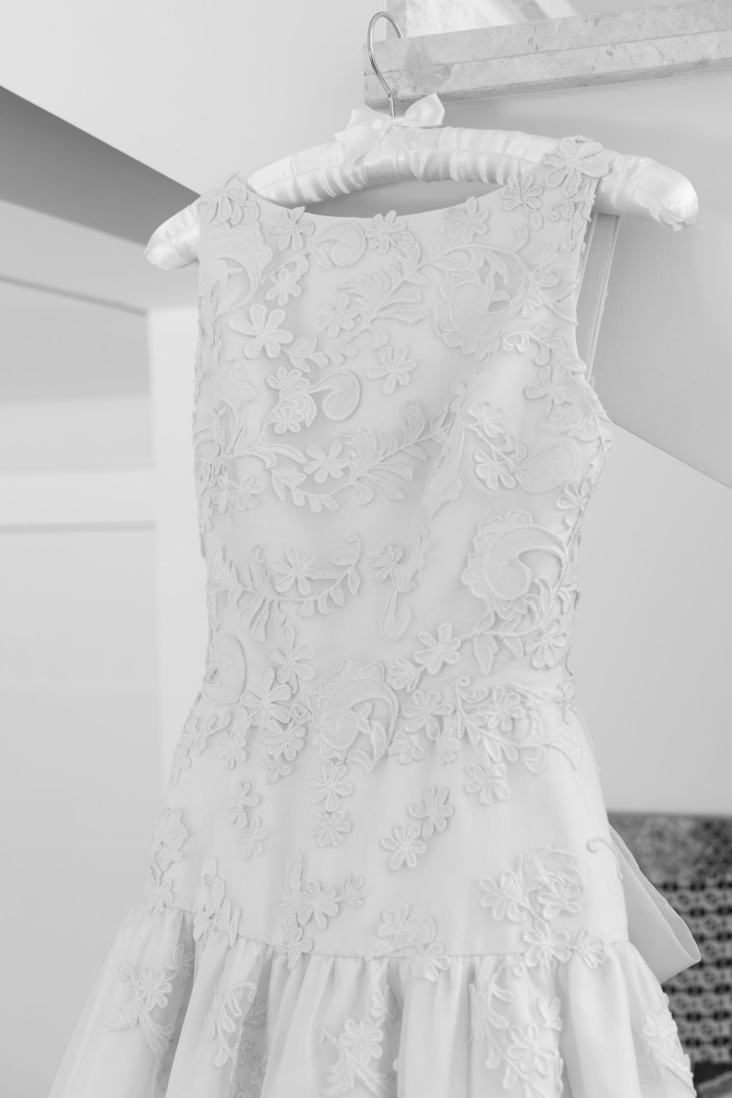 Close-up details of delicate white lace and embroidery patterns on a formal dress.