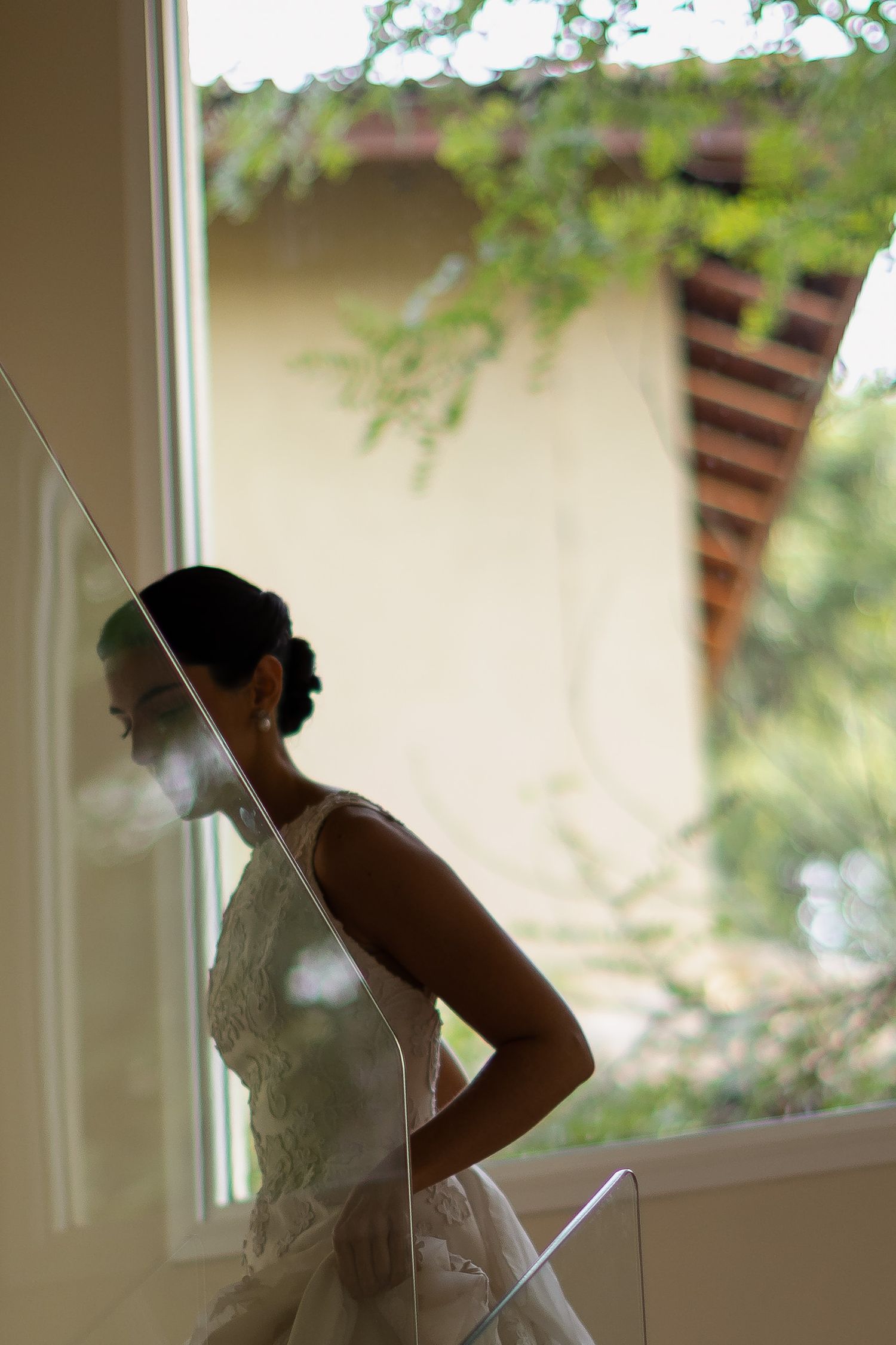 A bride in a white wedding dress is shown in a series of silhouetted poses near a window in soft natural light.