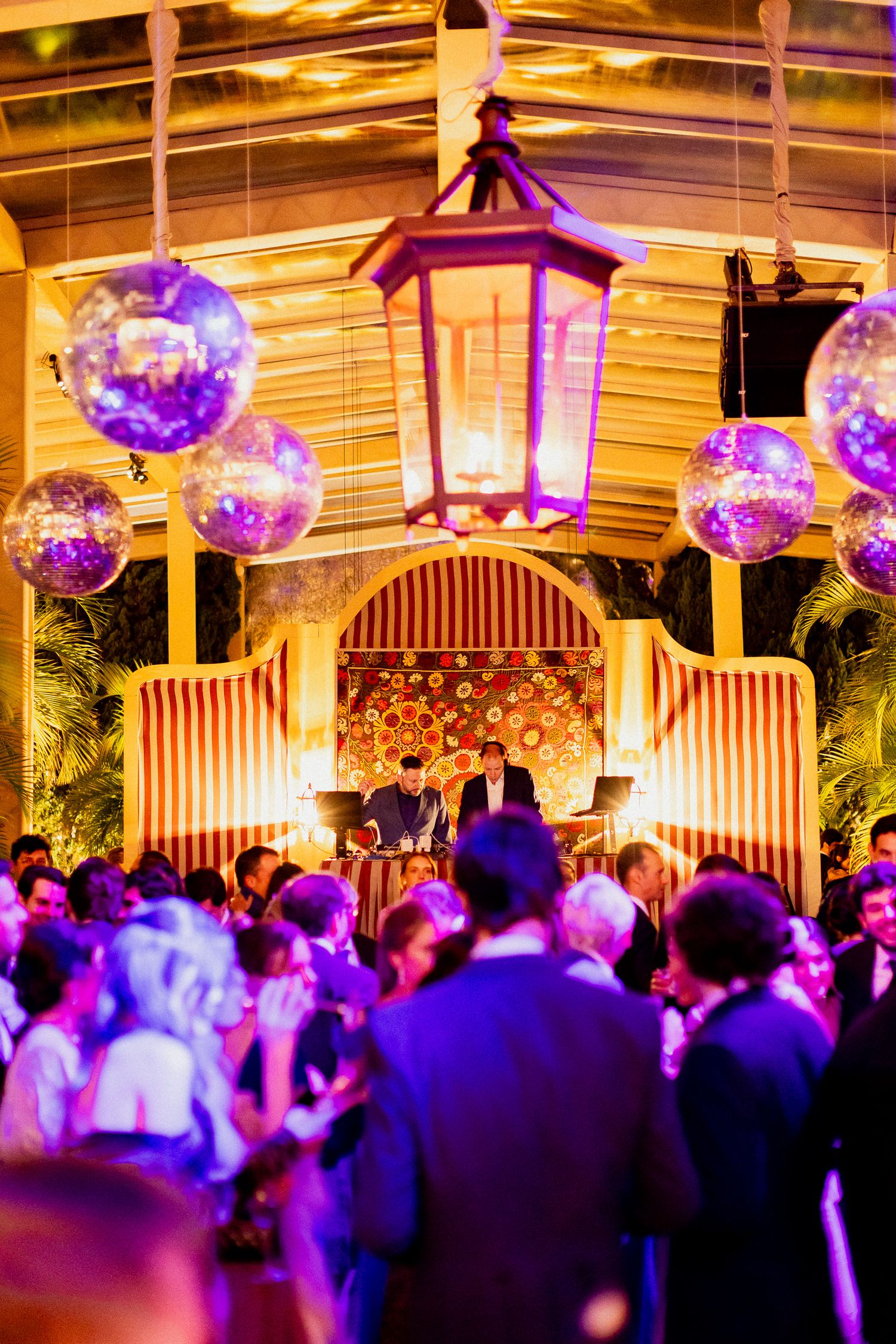 Elegant wedding reception with purple lighting, hanging lanterns and disco balls creating a magical atmosphere.