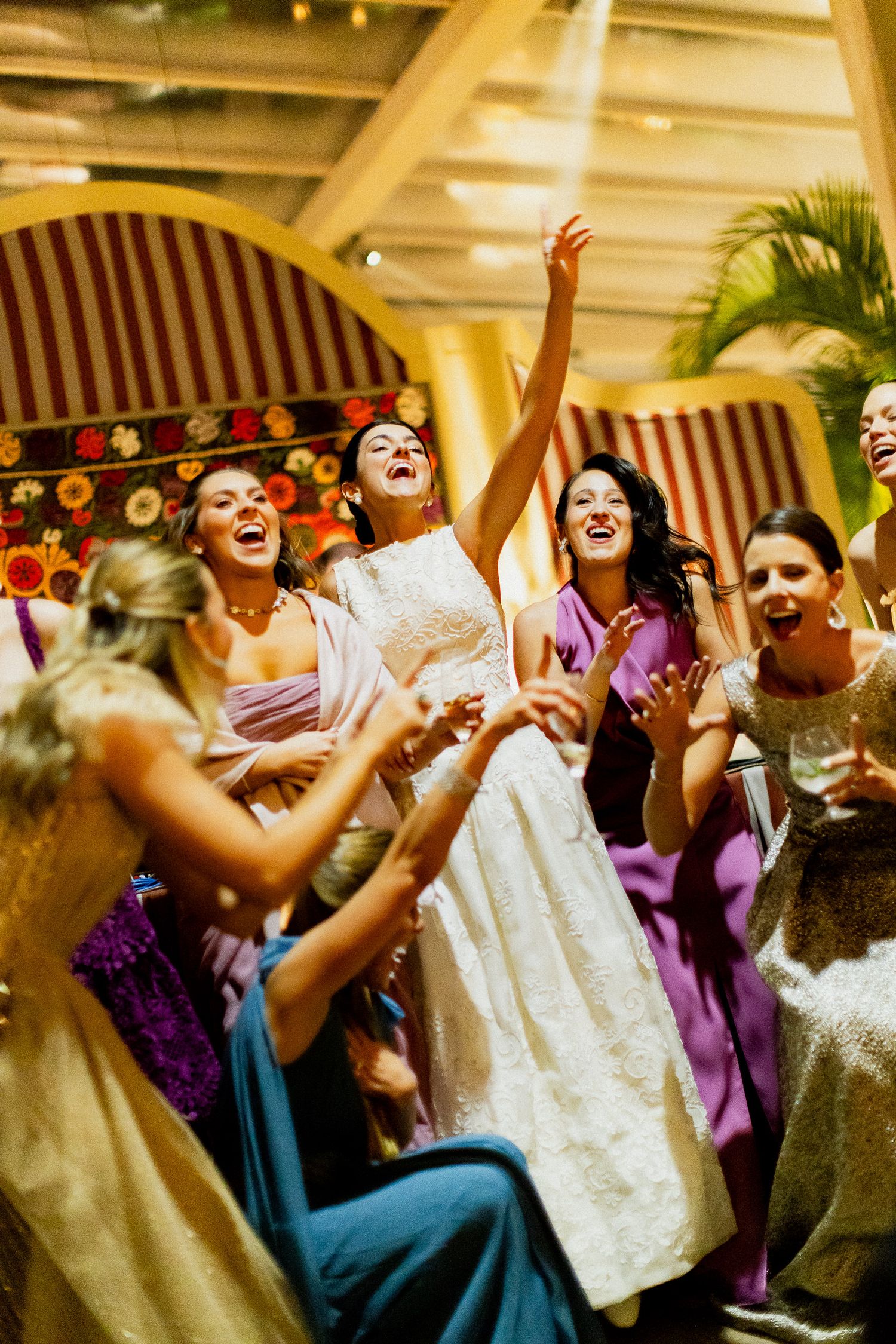 Wedding guests dance and celebrate joyfully at a reception with warm lighting and festive atmosphere.