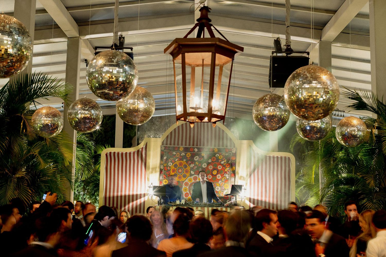 Glass orb decorations and lanterns illuminate an elegant outdoor wedding reception venue at night.