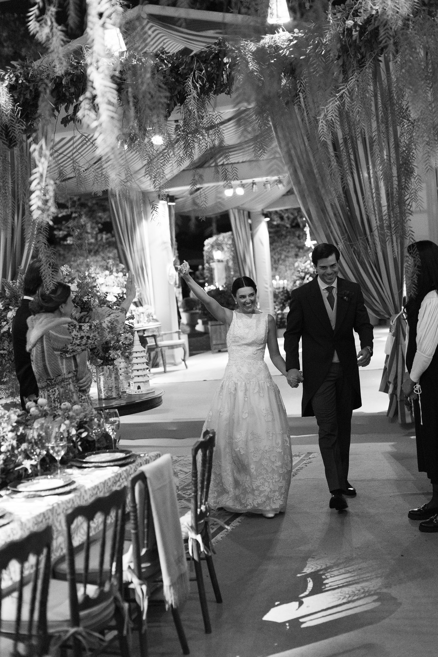 Black and white wedding ceremony photos show a couple walking down an elegantly decorated aisle.