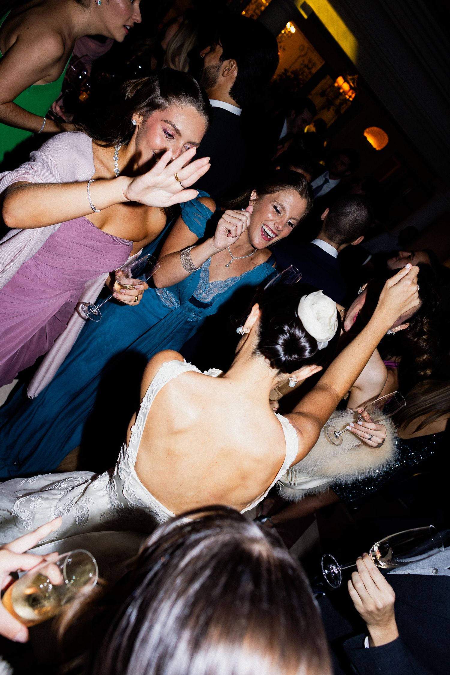 Lively crowd of party-goers dancing and celebrating at a dimly lit nightclub event.