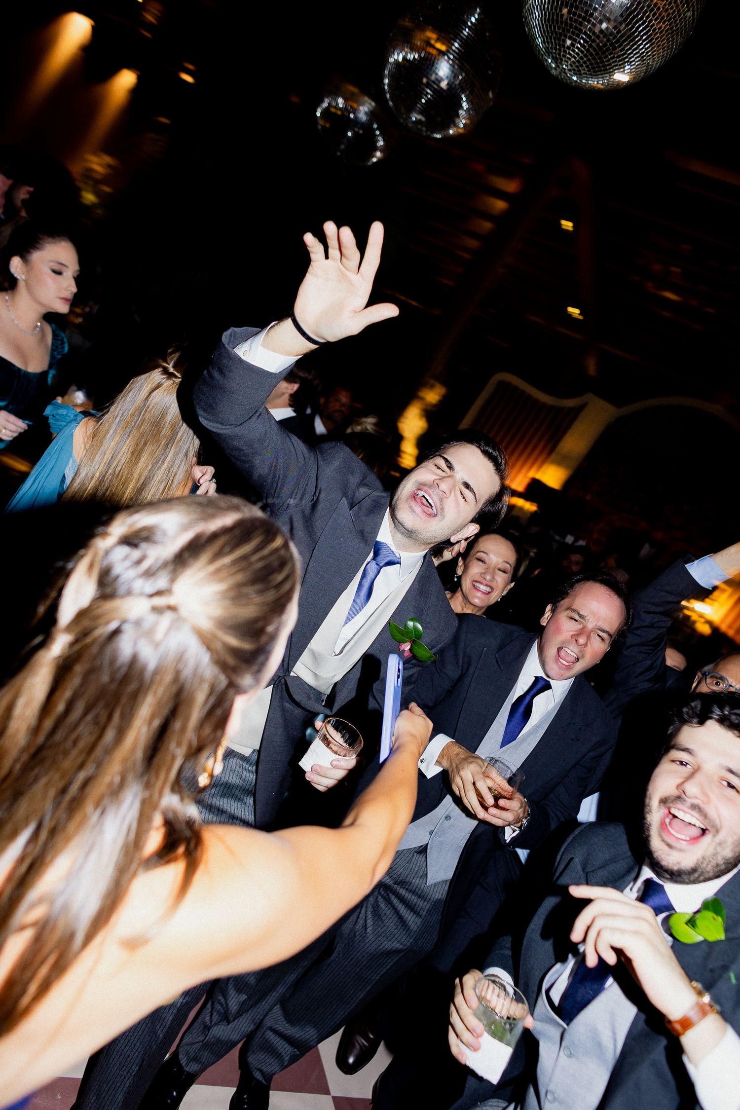 People dancing and celebrating at a formal event with dark lighting and energetic movements.