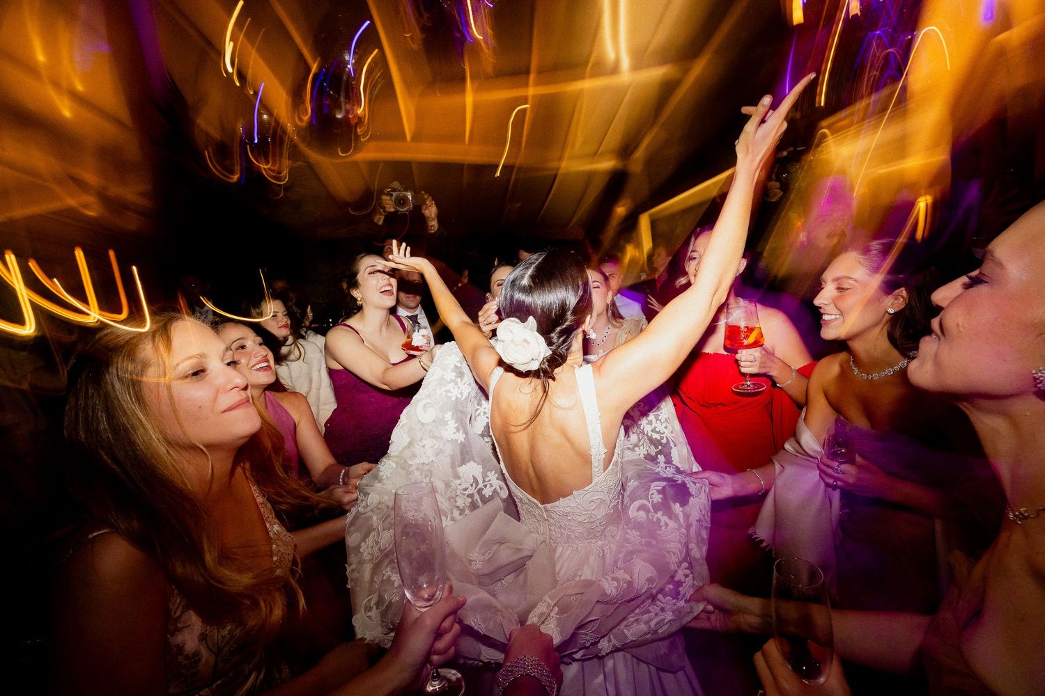 People dancing and celebrating at a lively party with colorful lighting and energetic atmosphere.