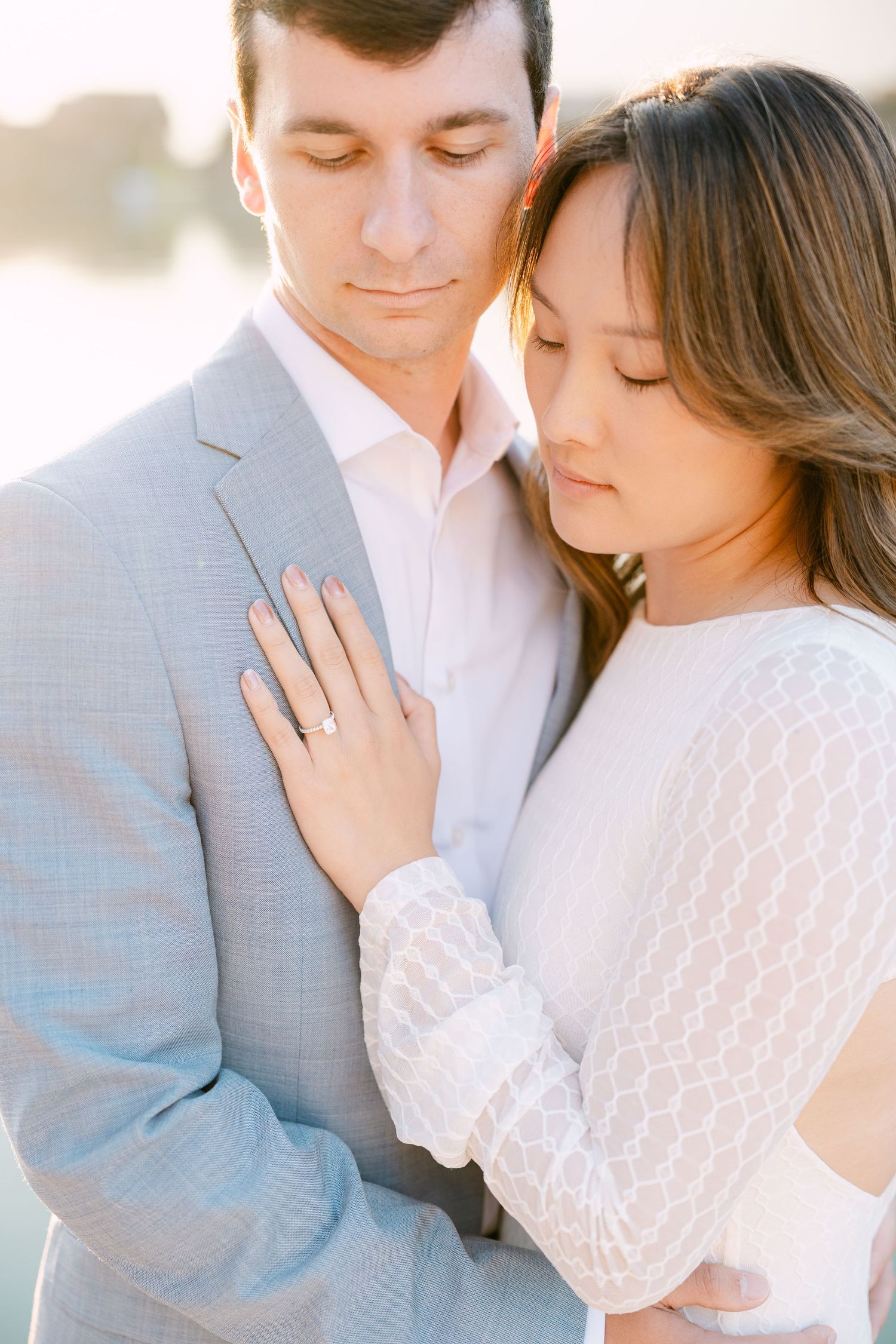 Romantic couple in soft light embrace wearing light colored clothing during engagement photo session in Iseltwald, Switzerland.