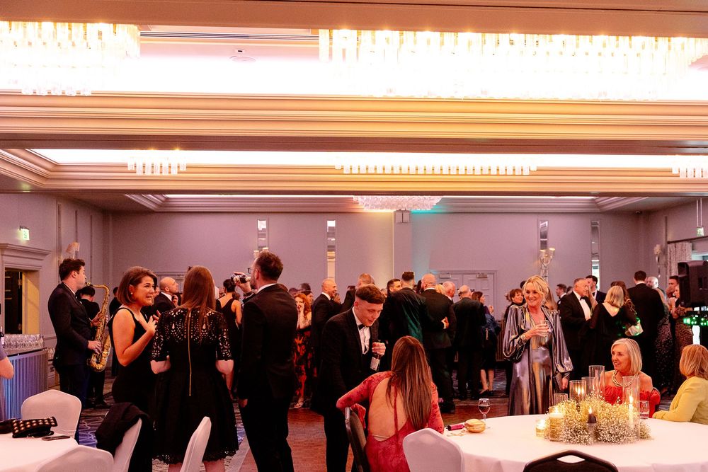 Wide view of an elegant wedding reception hall with guests gathered under crystal chandeliers.