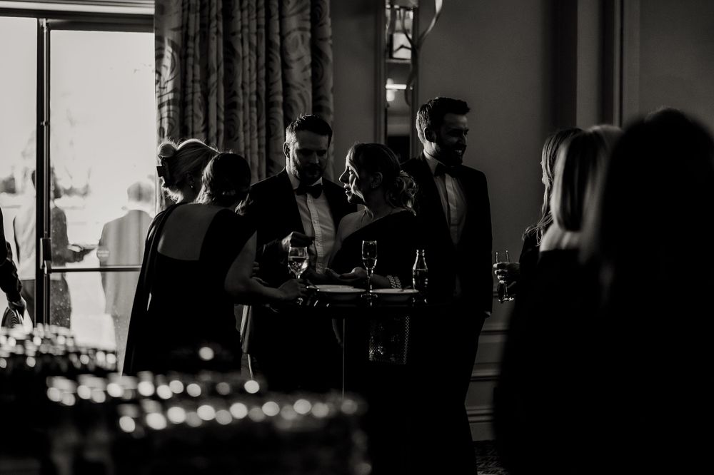 Dark silhouettes of people mingling at an evening indoor reception.