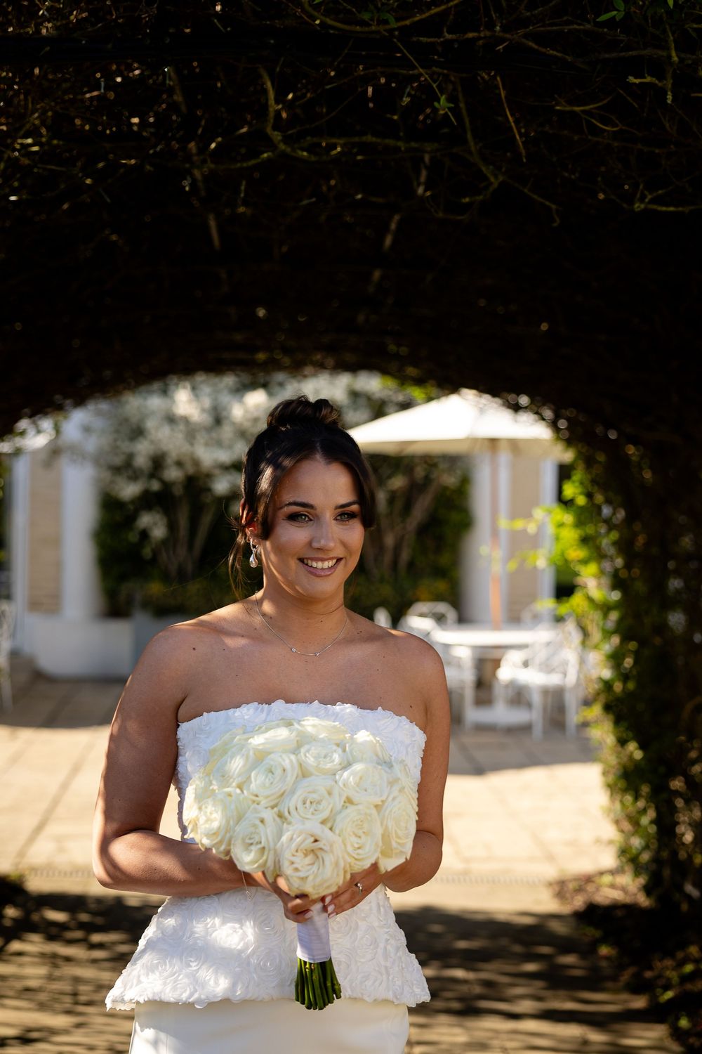 A wedding photoshoot in a garden setting featuring a white bridal bouquet of roses.