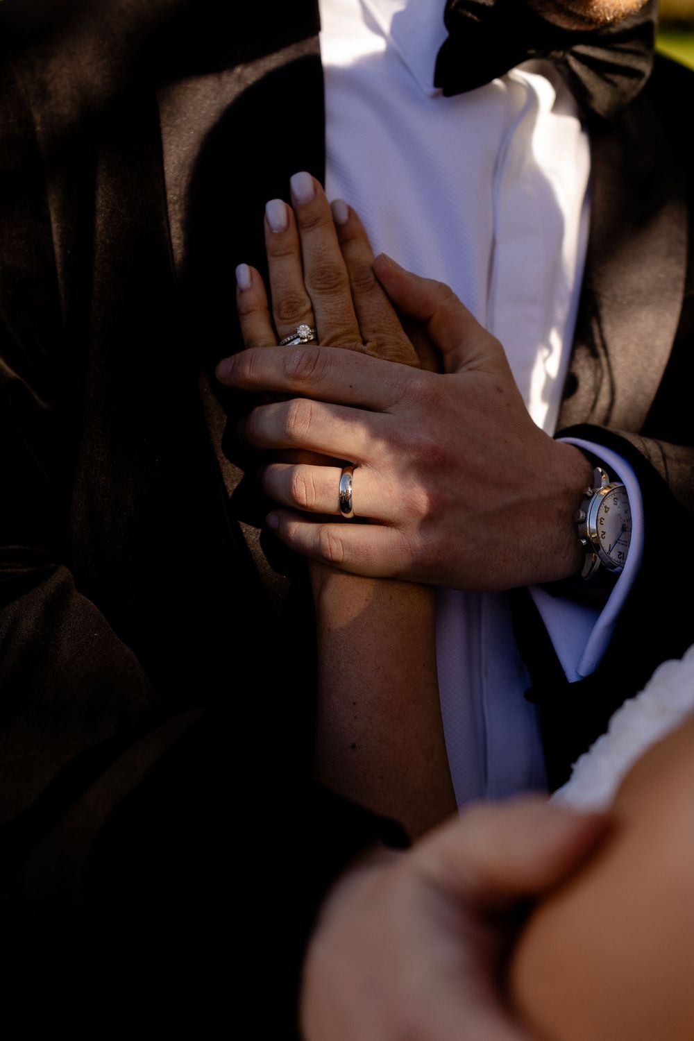 Close-up of hands with wedding rings during an intimate moment on the dance floor.