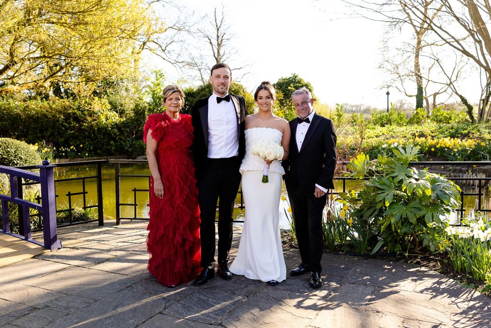 Wedding party posing together in a beautiful garden setting with golden sunlight.