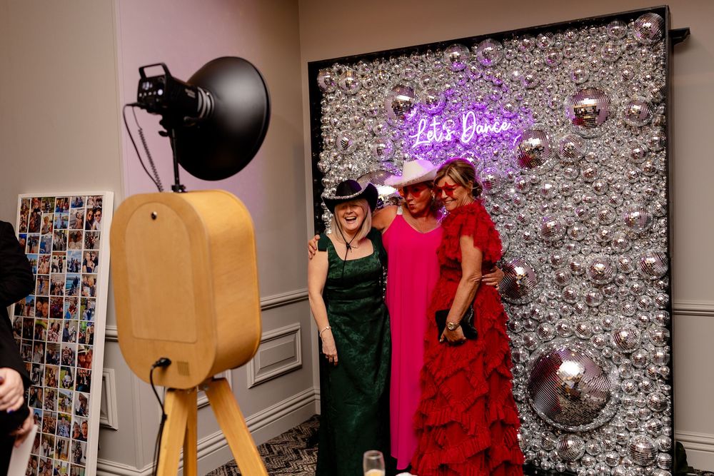 Party scene with decorative lighting and silver backdrop showing people in colorful outfits enjoying themselves.