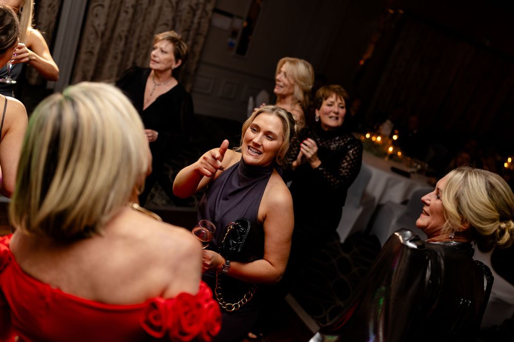 People dancing and laughing at a lively party with dim lighting and festive atmosphere.