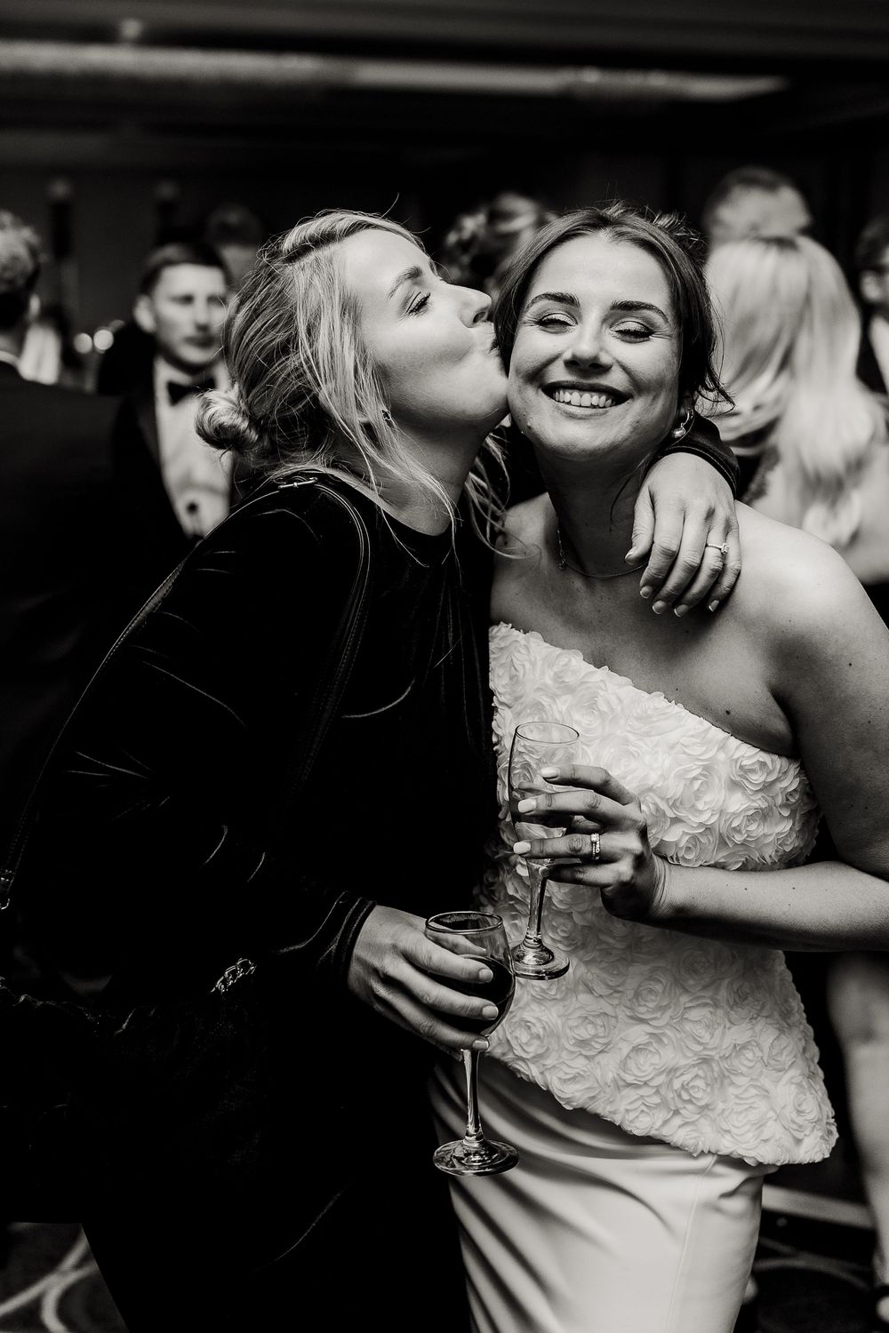 Black and white candid moments of celebration and embraces at an elegant wedding reception.