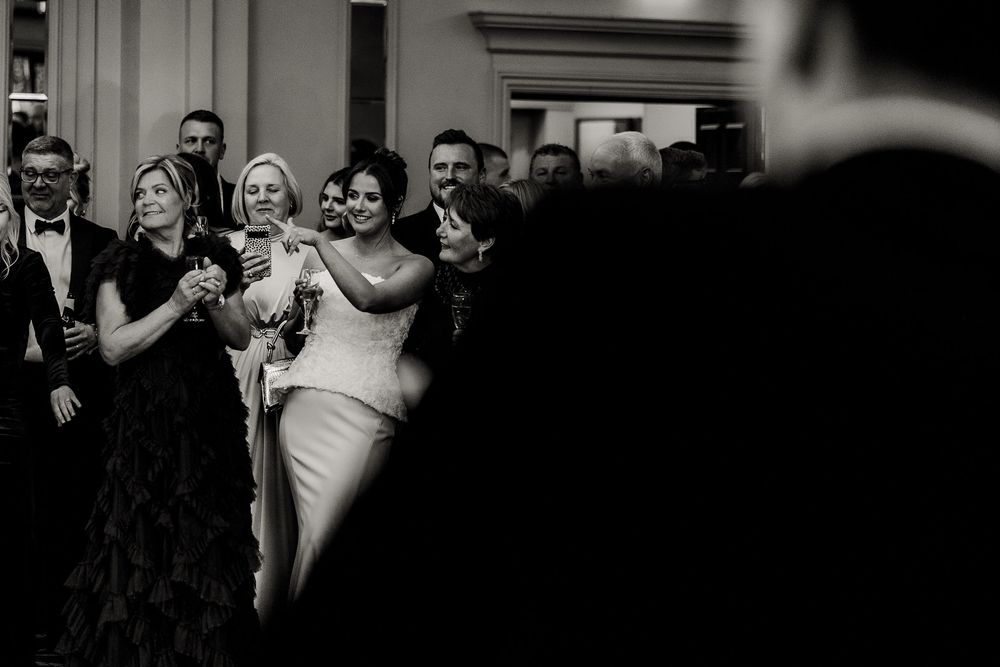Guests enjoying themselves at an elegant indoor wedding reception with dramatic lighting.