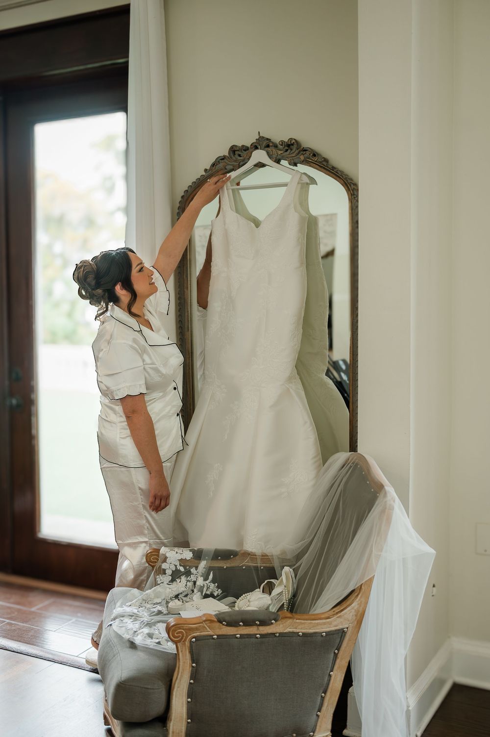 Behind the scenes wedding preparation showing dress fitting and adjustments in a bright room.