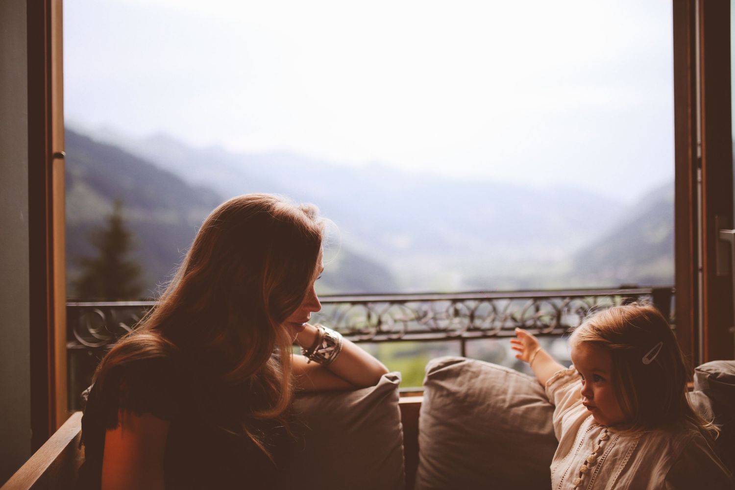 Cozy mountain view from a balcony with comfortable seating and misty valley vista.