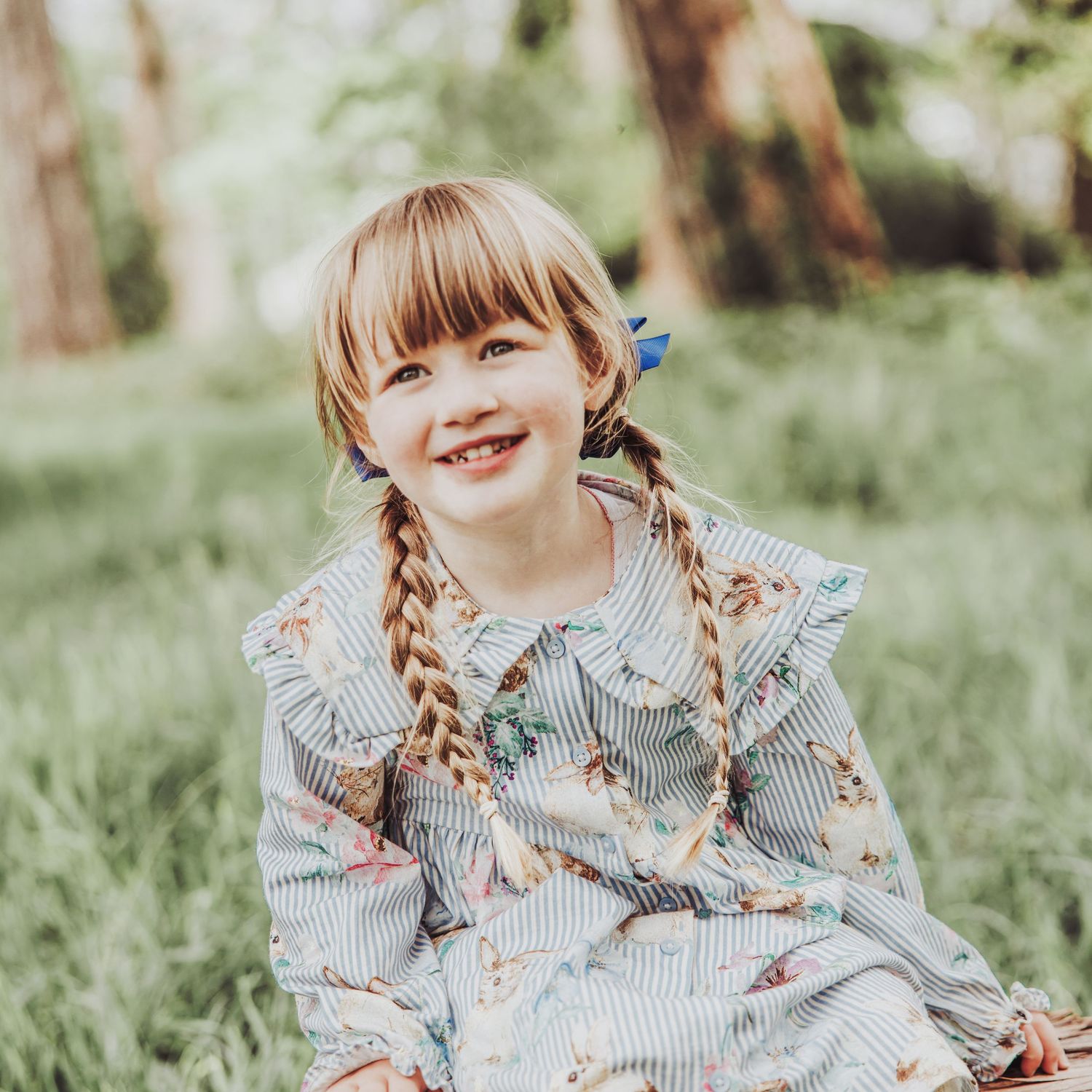 Little girl sitting and laughing in a woodland.