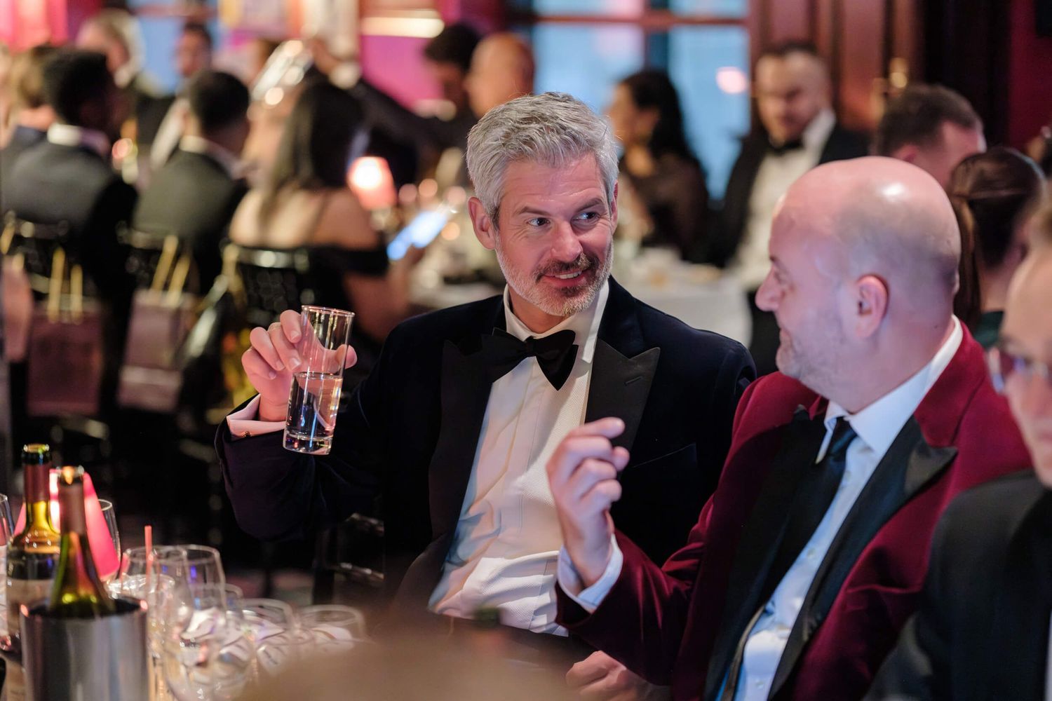 Candid black and white photos show people engaged in lively conversations at an elegant formal event.