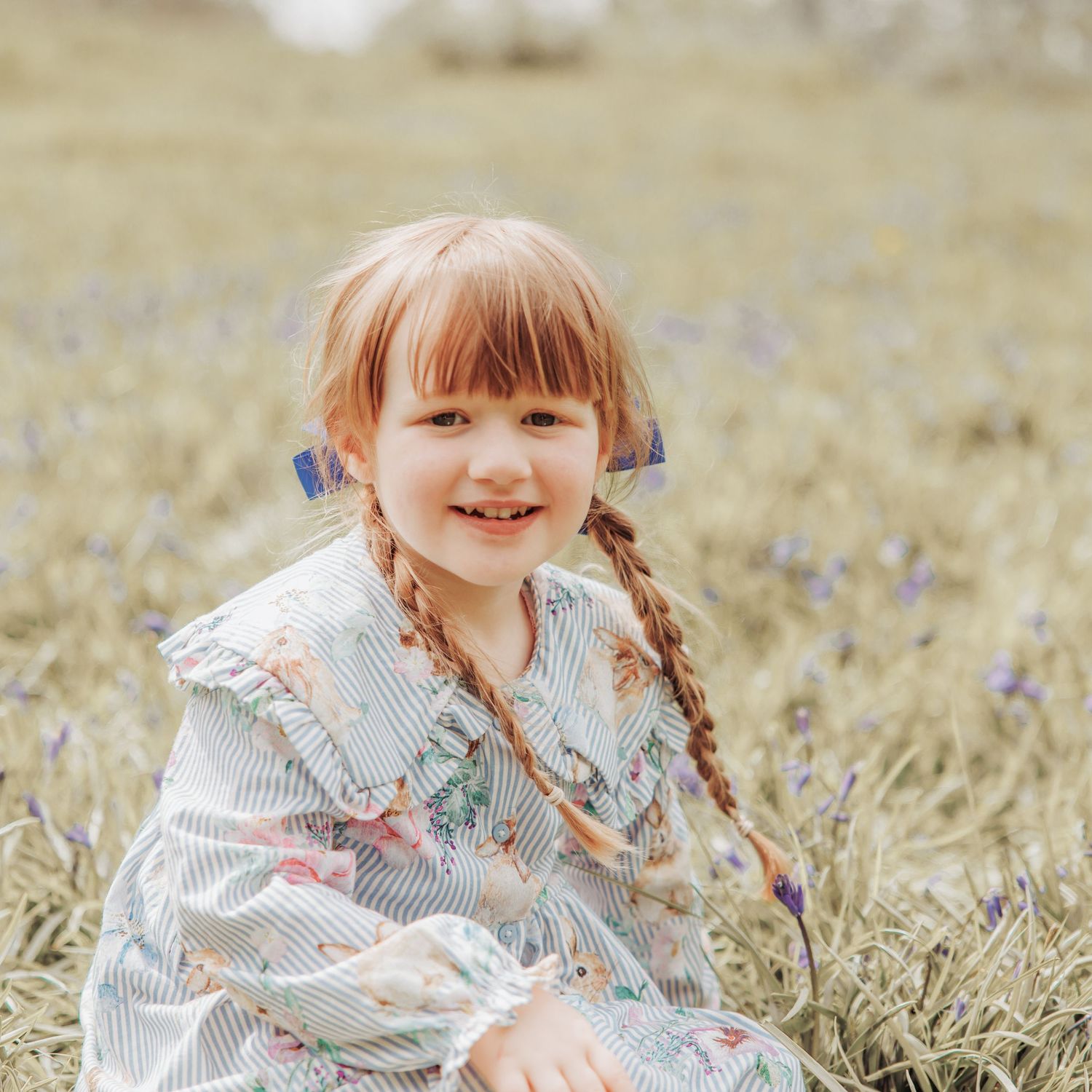 Young girl sitting in a bluebell field smiling