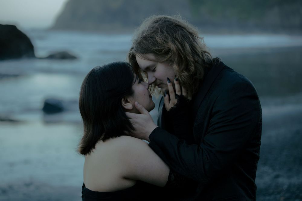 Intimate romantic scene unfolds on a moody beach at dusk.