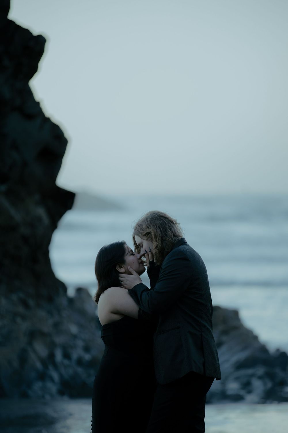A moody black and white photo series of a couple sharing an intimate moment by the sea.