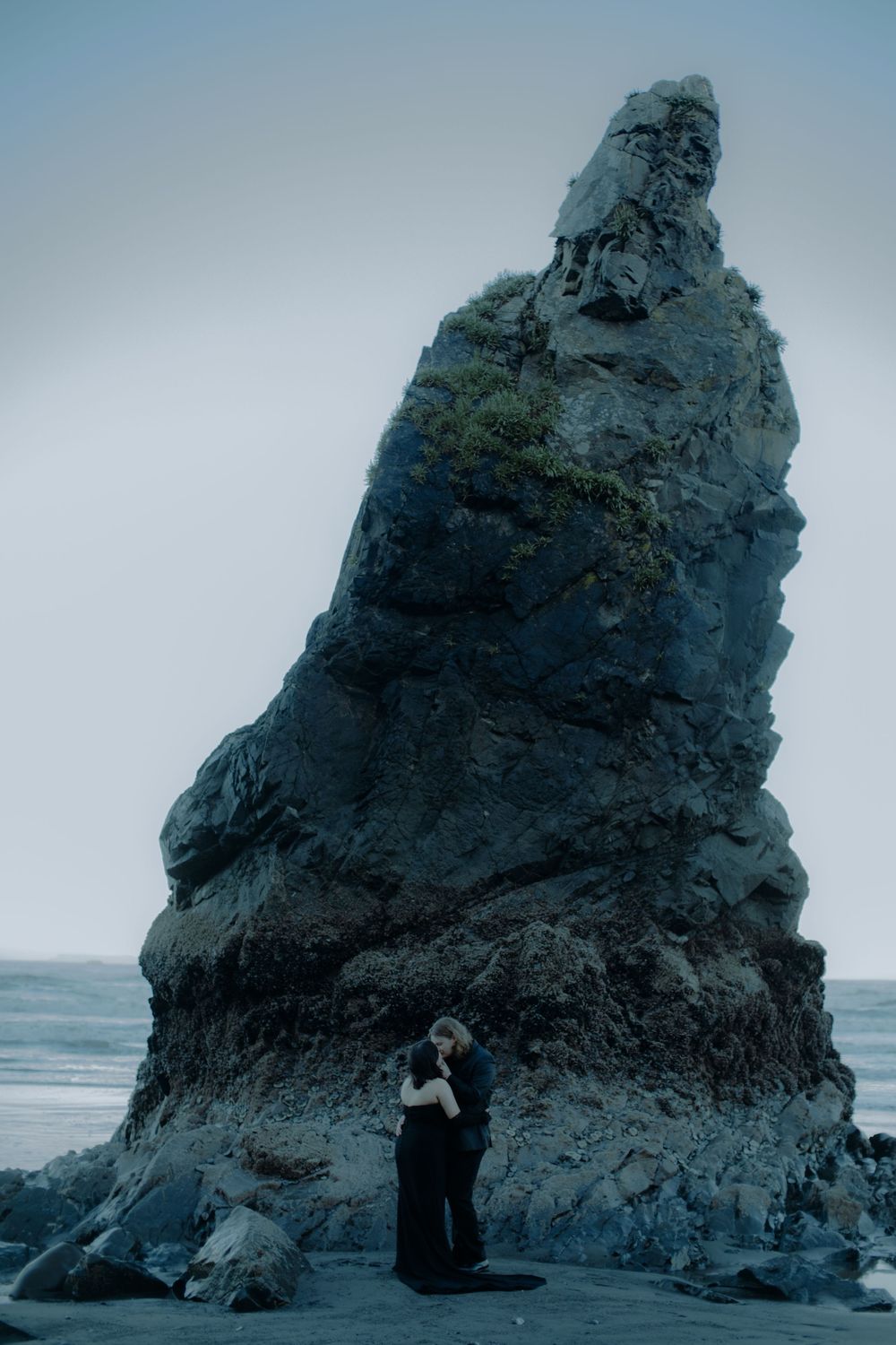 Dramatic coastal landscape photos with figures posed near a large sea stack.