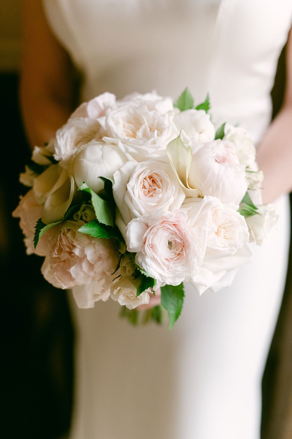 Close-up details of delicate pink and white roses adorning a wedding cake in a romantic floral arrangement.