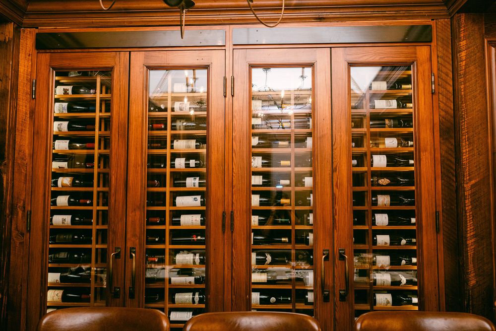 Panoramic view of built-in wine storage cabinets with glass doors in a wood-paneled wall.
