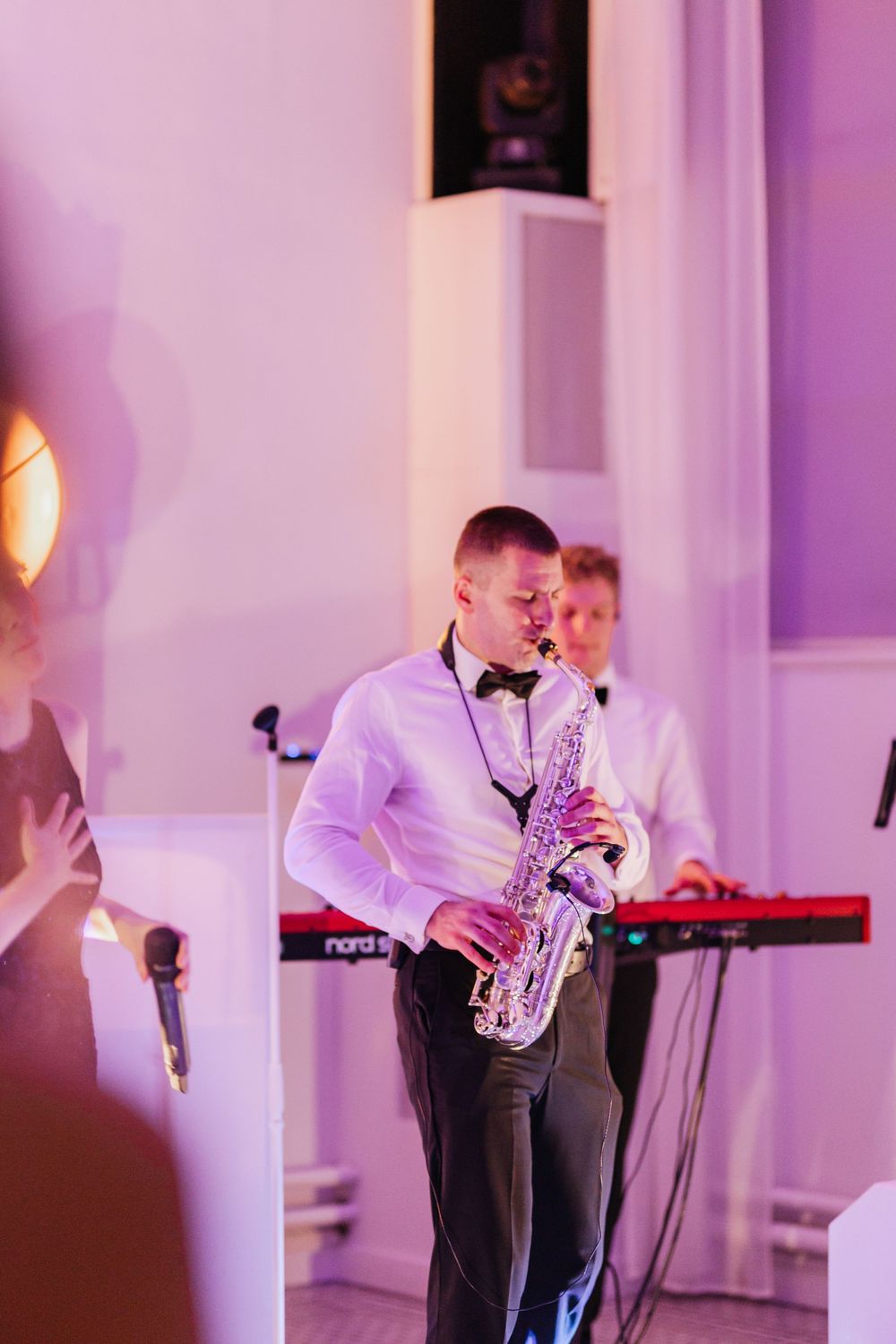 Saxophone player performs at elegant venue with purple lighting and formal attire.