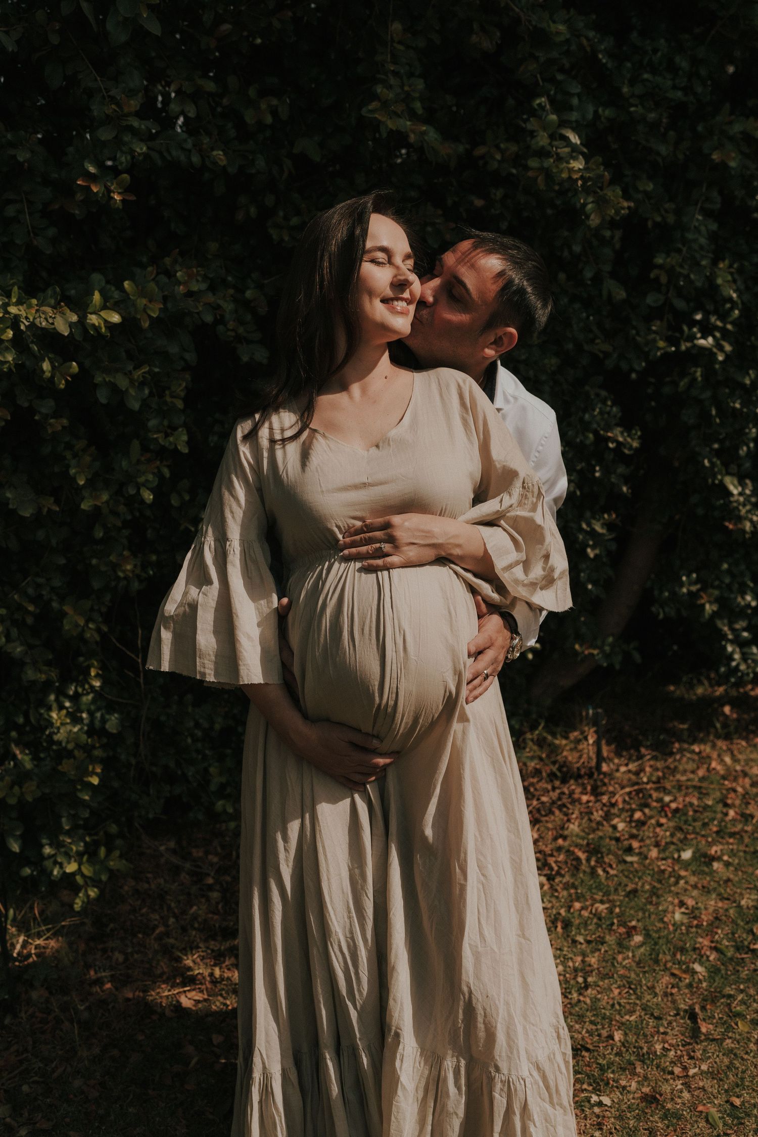 Artistic maternity photography series showing loving moments between a couple in ethereal white dresses outdoors.