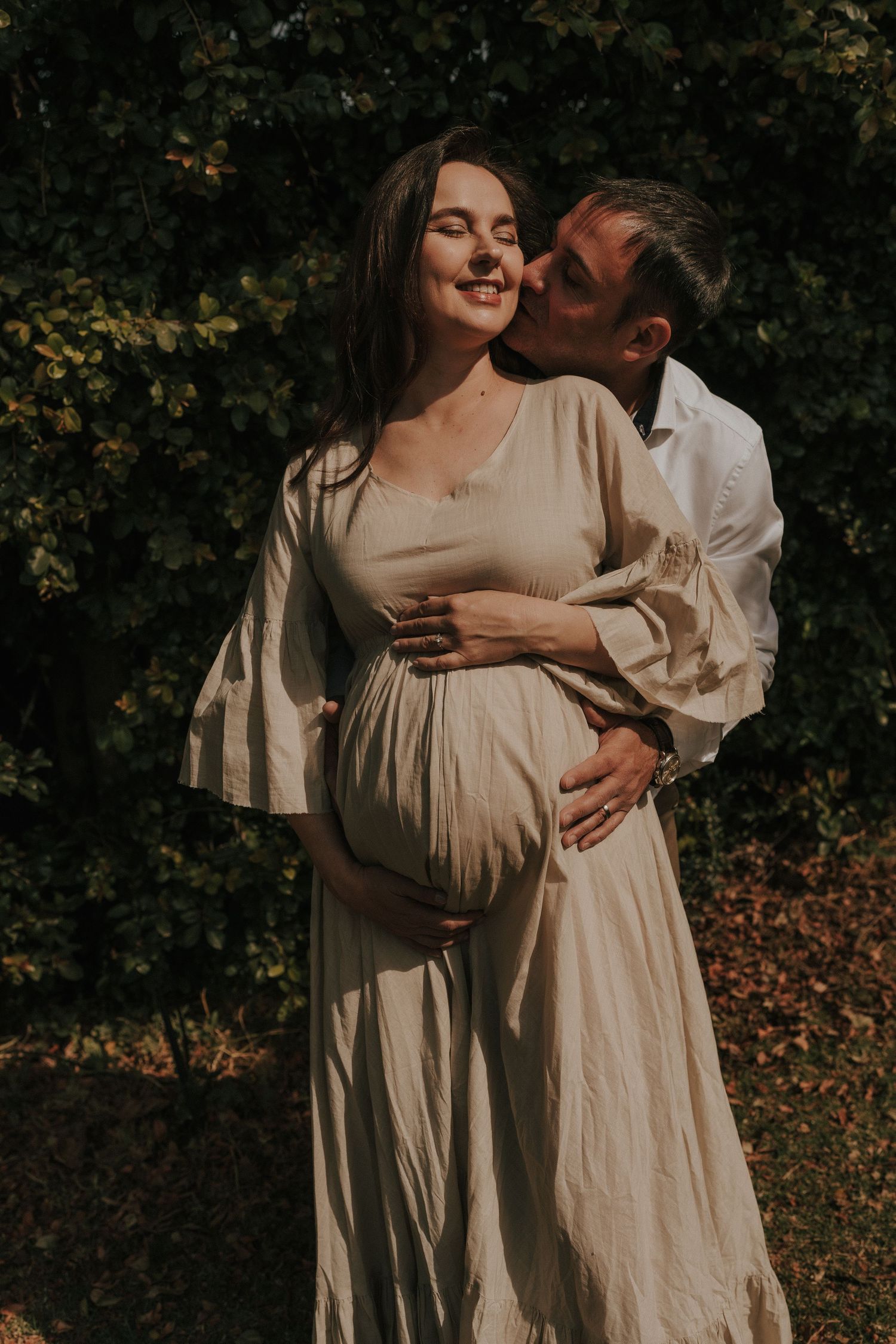 Golden hour maternity session capturing intimate moments between an expectant couple in light neutral clothing.