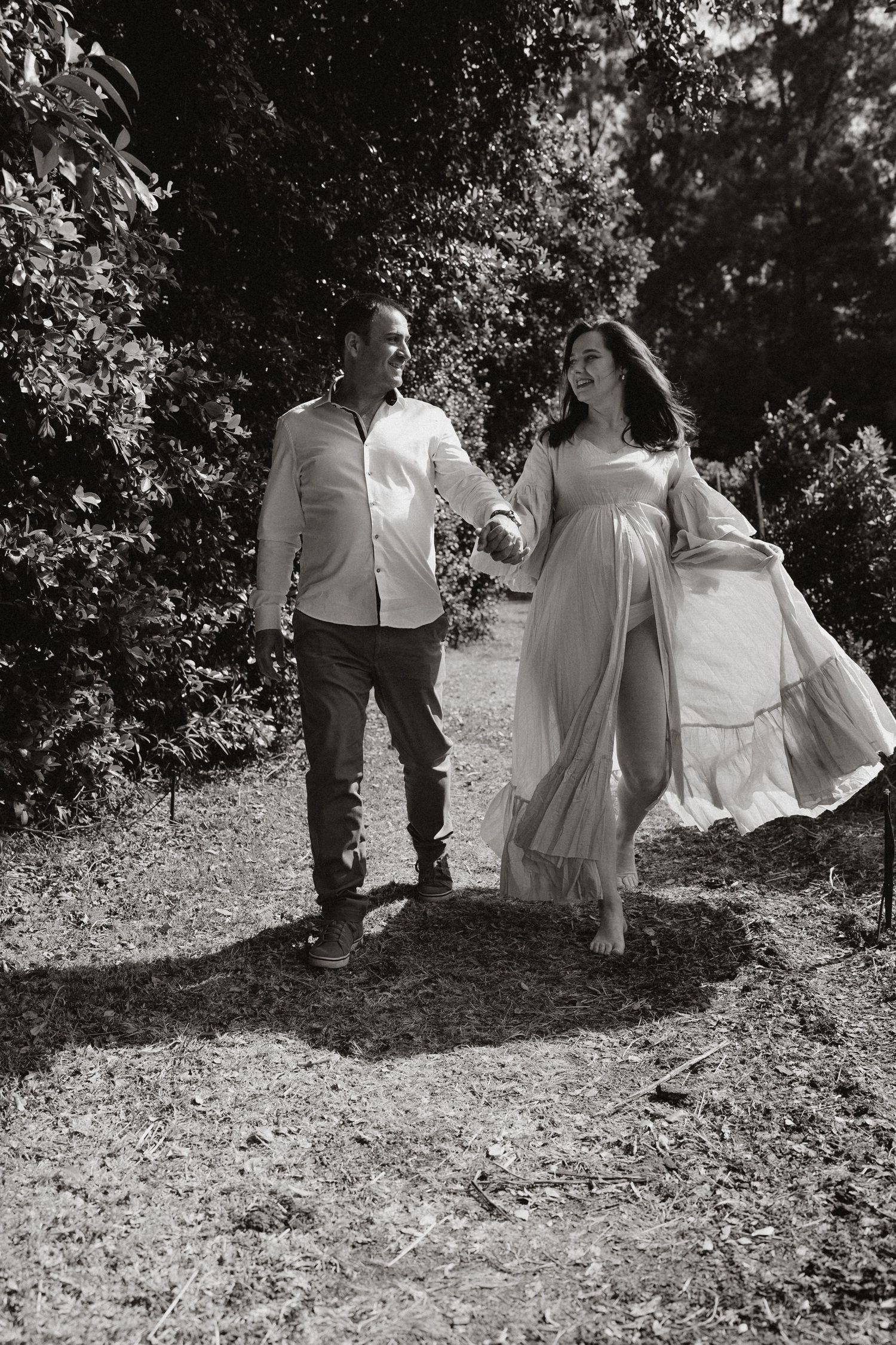 Black and white photograph of a couple walking together on a leaf-covered hillside path.