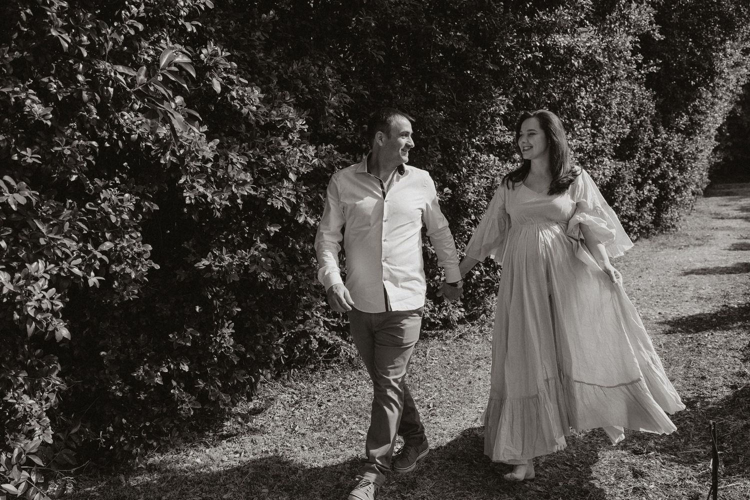 A couple embraces outdoors in a romantic photoshoot among autumn trees and dappled sunlight.