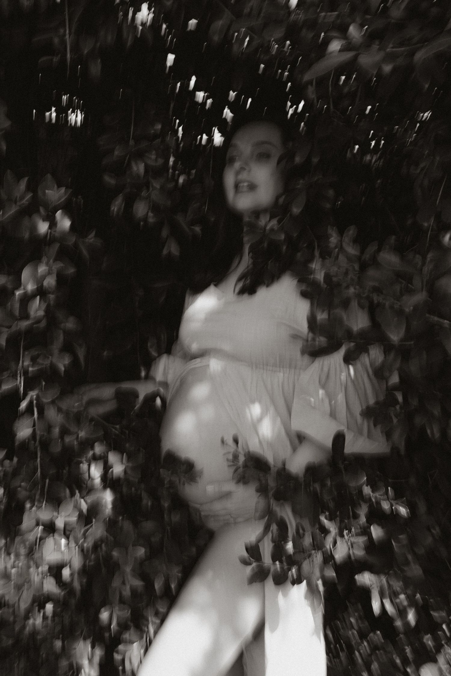High contrast maternity portrait with flowing fabric and natural light effects.
