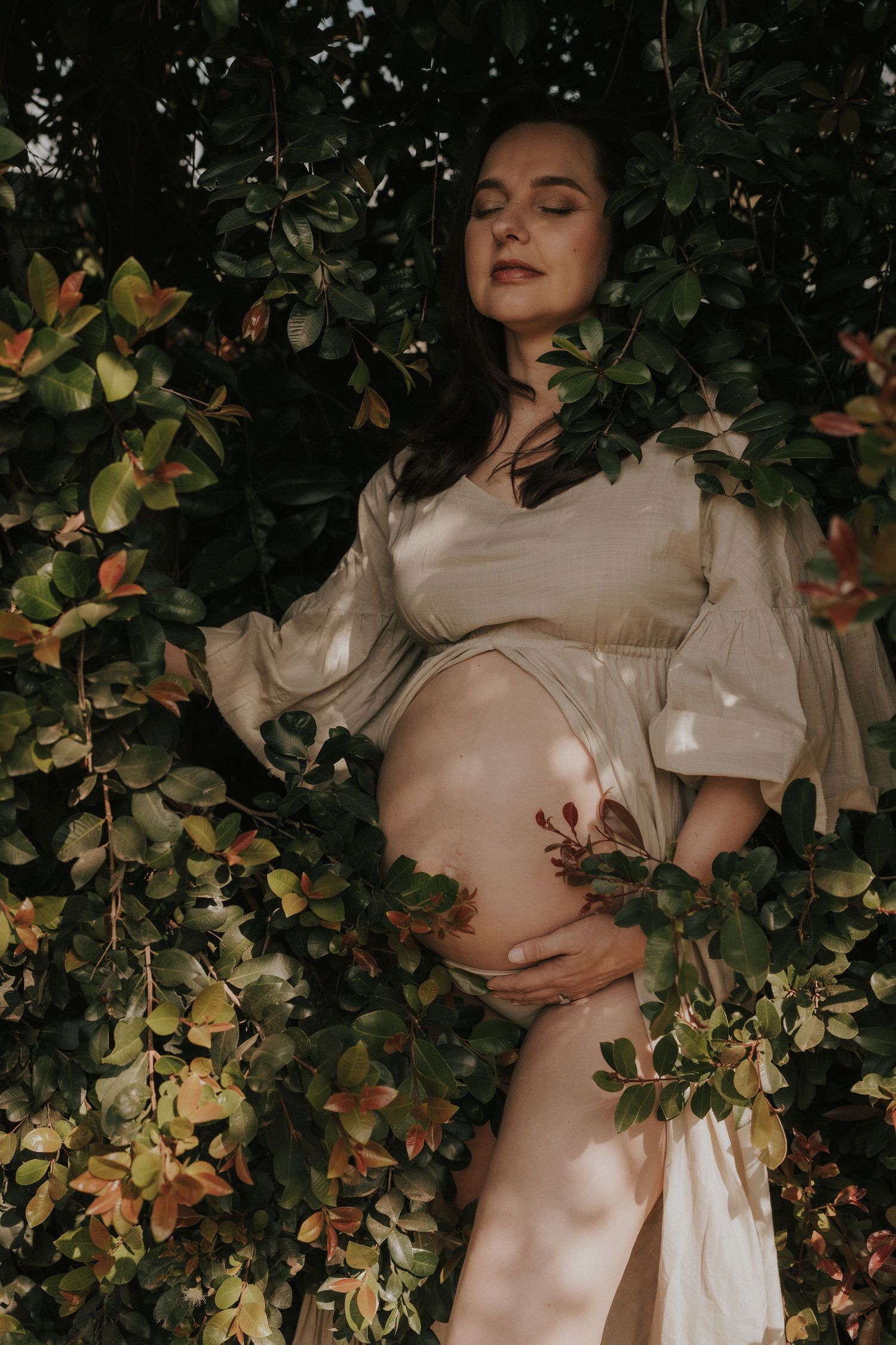 Artistic pregnancy photo with cream dress among autumn foliage.