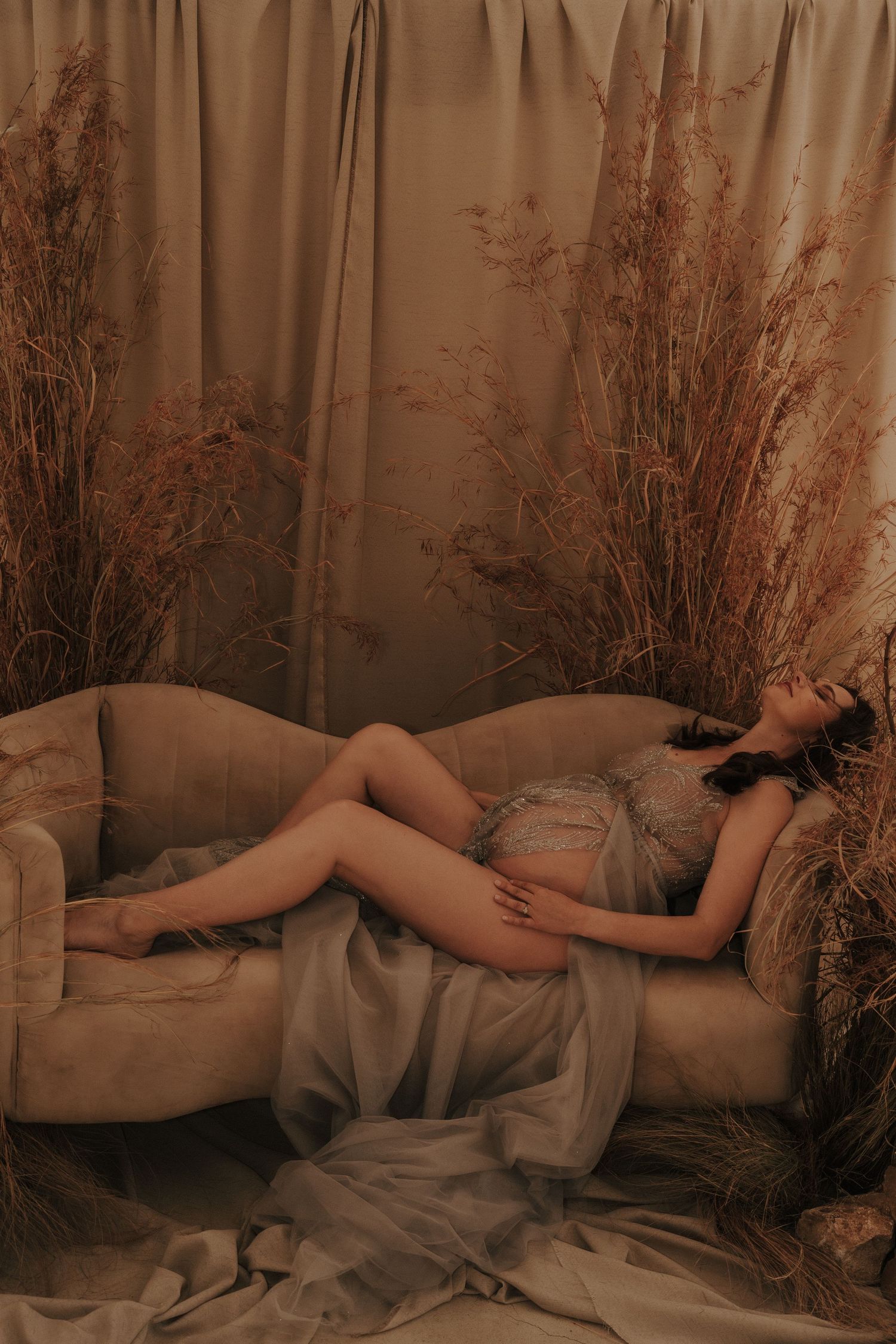 Artistic boudoir photography with dried pampas grass and soft drapery in muted tones.