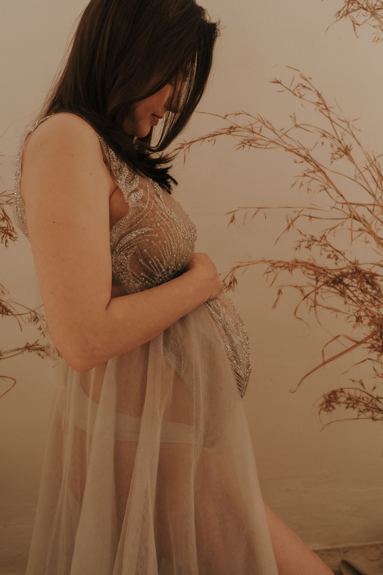 Intimate maternity portrait series with warm tones and natural elements.
