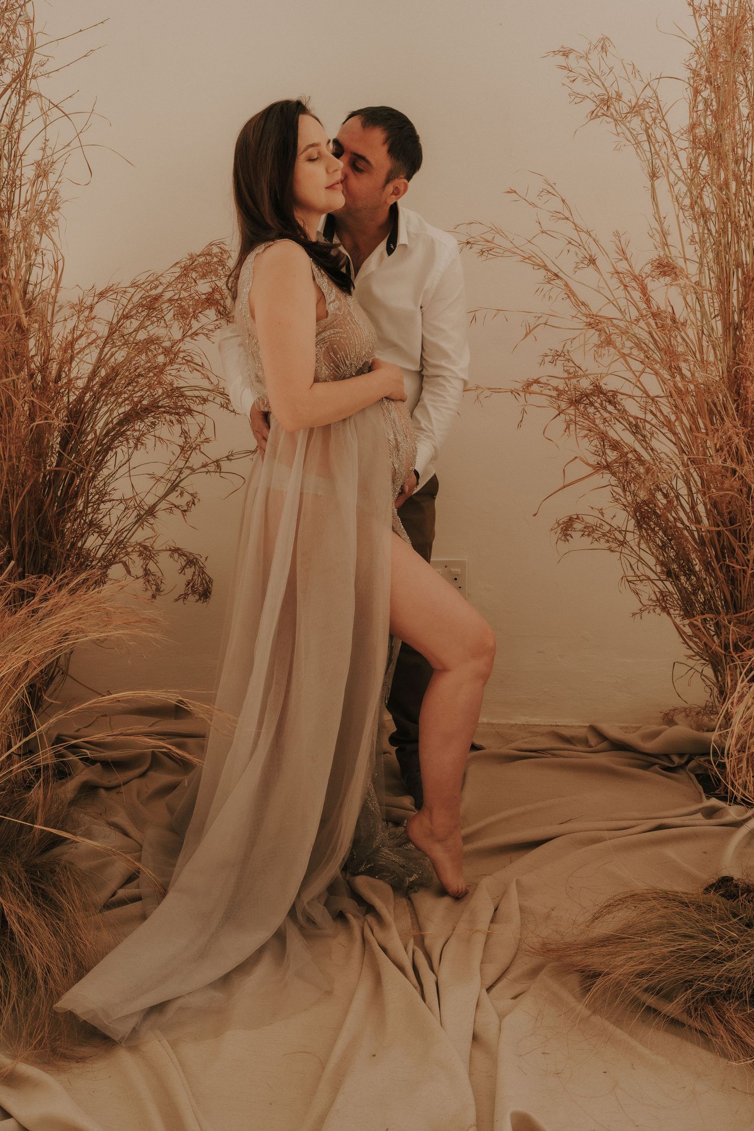 Romantic couple's photoshoot with flowing fabric and dried floral arrangements.