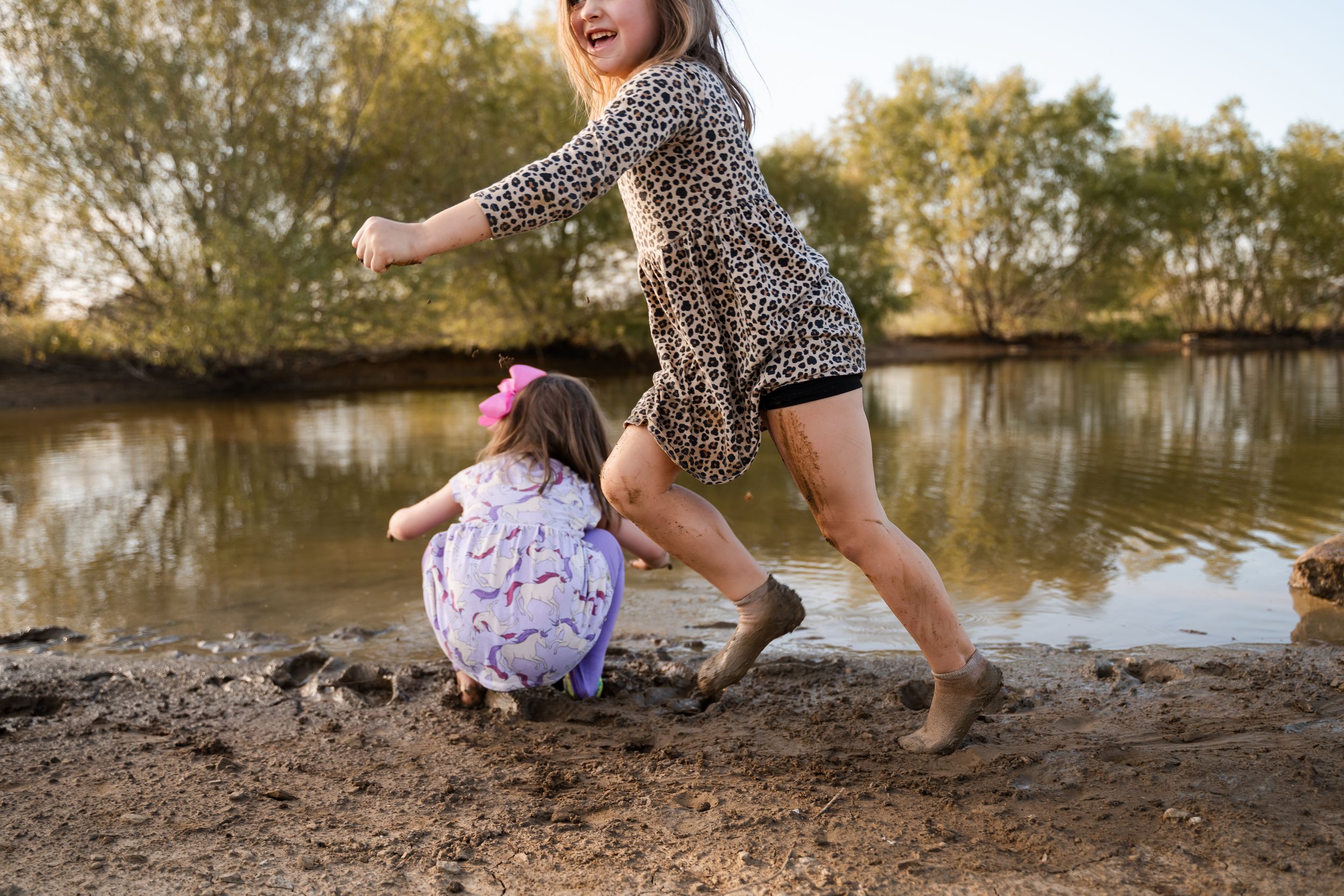 Children play in muddy pond during a family documentary photography session in Tulsa, Ok