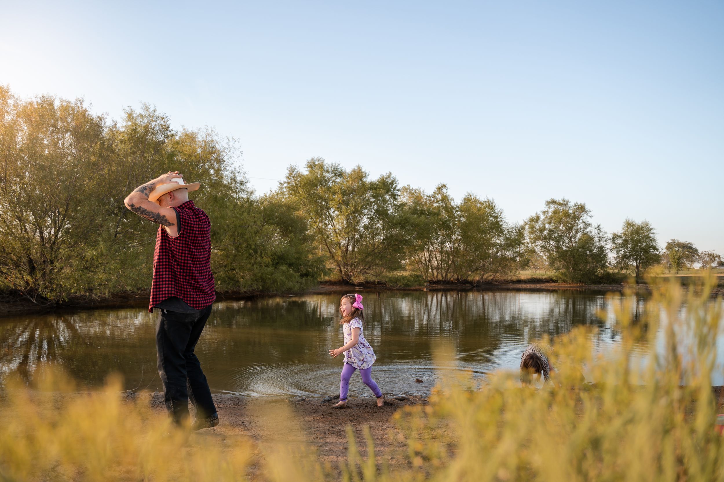 Tulsa Father watches over his daughters playing in a pond during a family documentary photography session