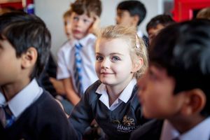 Students in school uniforms gather together in a classroom setting during an educational activity.